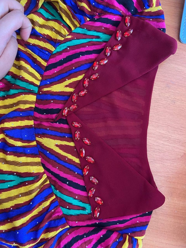 Close-up of red crystals hand-sewn on deep red collar